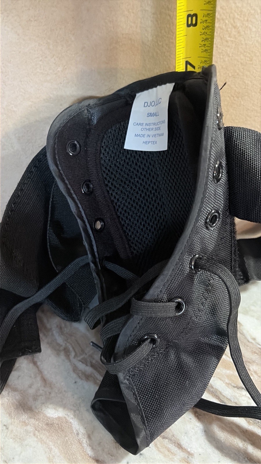 This is a black DJO LLC “Heptex” medical ankle brace, size small.